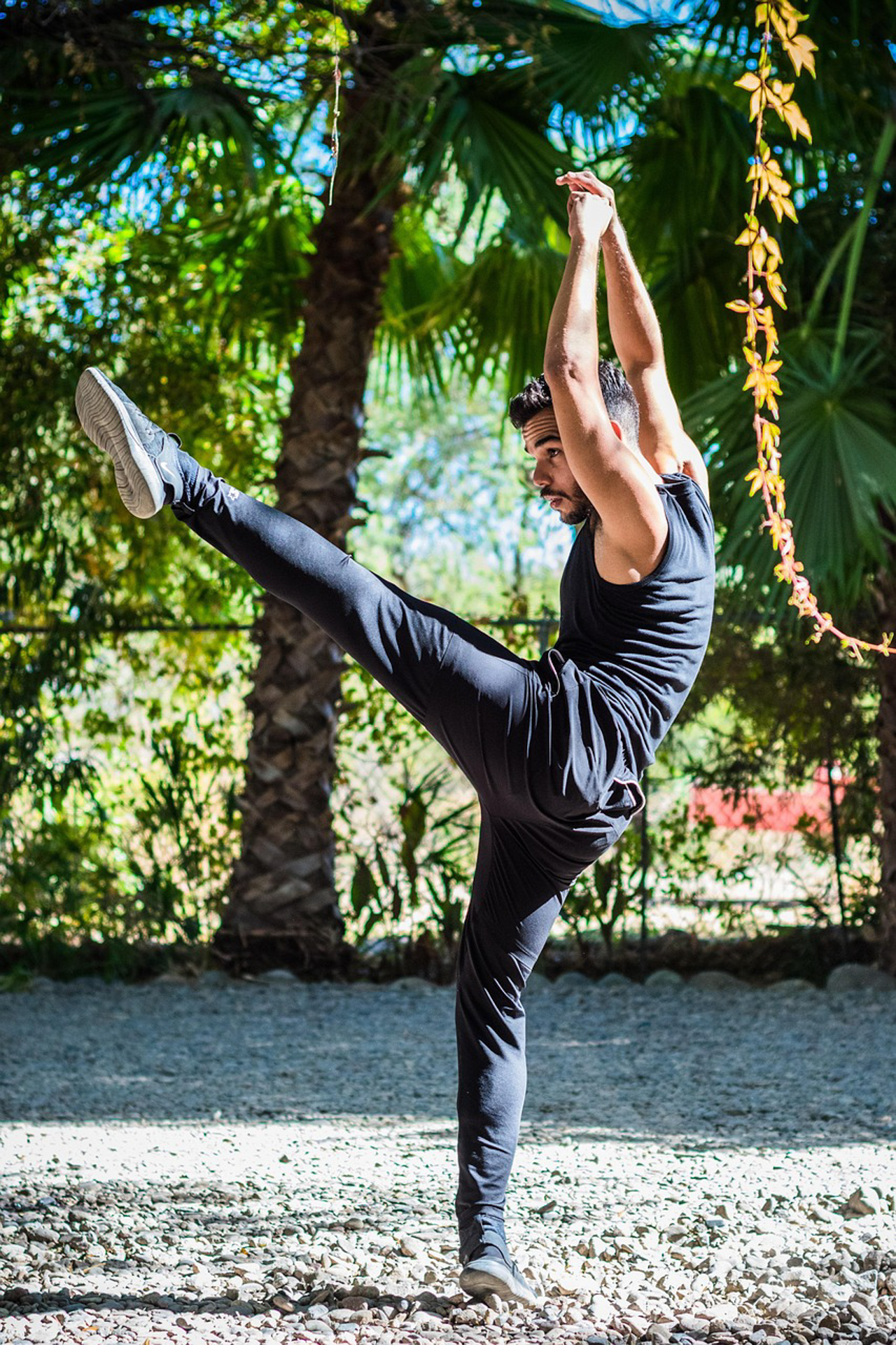 Man performing a high kick outdoors, highlighting balance and flexibility rooted in strong stable feet.
